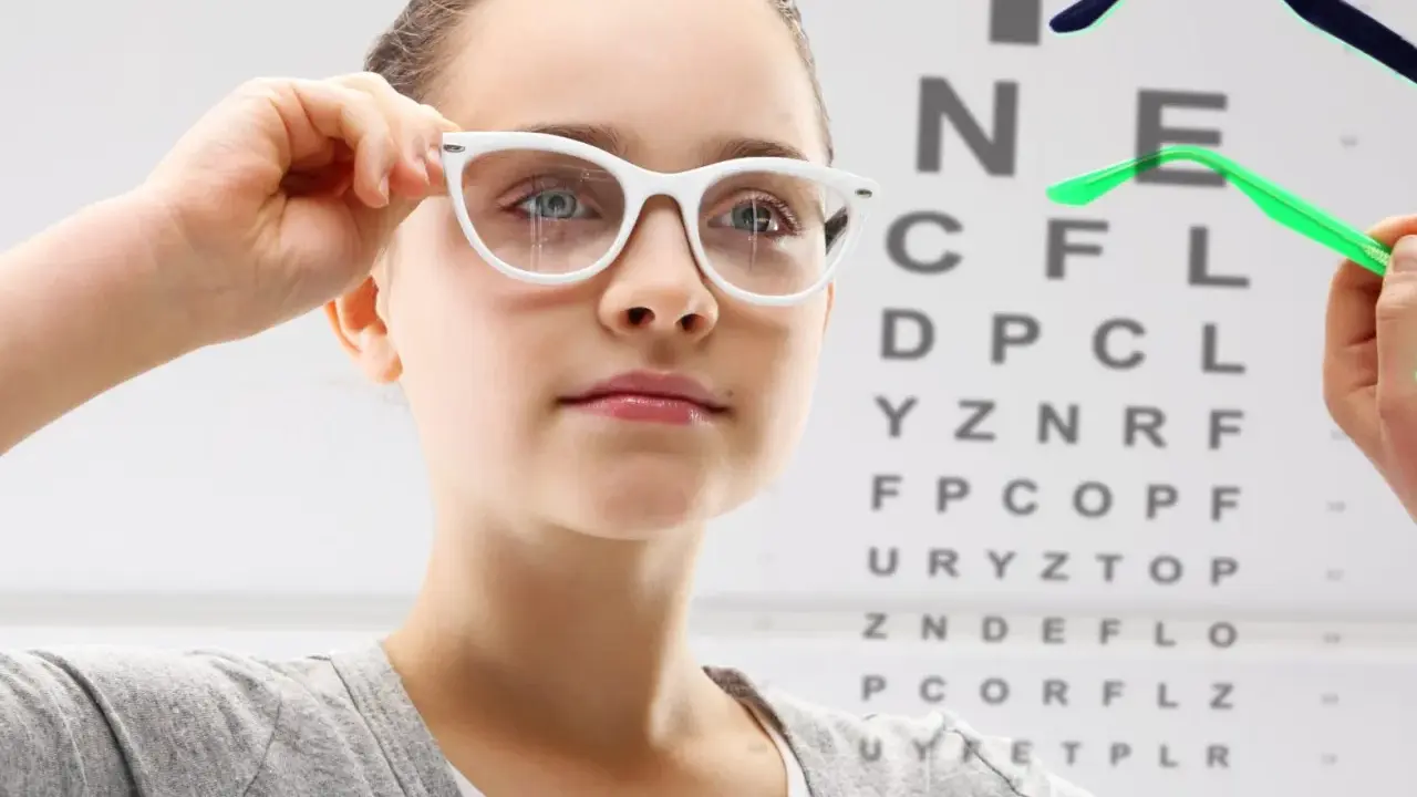 Dziewczynka z okularami przed tablicą Snellena. Czy -1.25 to duża wada wzroku?