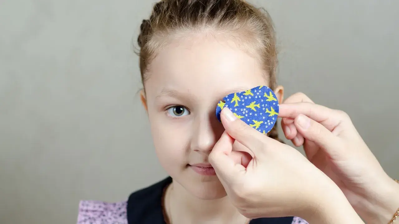 Dziecko z astygmatyzmem zakłada plaster na oko. Kiedy okulary nie wystarczają, taka metoda pomaga wzmocnić wzrok.