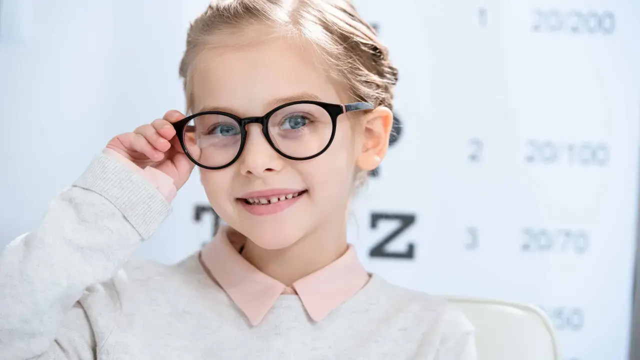 Uśmiechnięta dziewczynka z okularami, u której wykryto bardzo dużą wadę wzroku u dziecka.