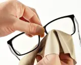 Dłonie czyszczą soczewki okularów miękką ściereczką. To jak wizyta u optyka, by zapewnić idealną ostrość widzenia.