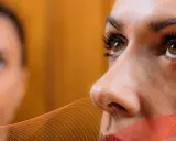 Zbliżenie na twarz kobiety, która wykonuje ćwiczenia na poprawę wzroku. W tle widać drugą osobę.