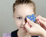 Dziecko z astygmatyzmem zakłada plaster na oko. Kiedy okulary nie wystarczają, taka metoda pomaga wzmocnić wzrok.