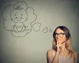 Kobieta w okularach myśli o dziecku. Czy wada wzroku a poród to powód do obaw?