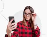 Kobieta w okularach robi selfie telefonem, zastanawiając się, czy na zdjęciu do dowodu można mieć okulary.