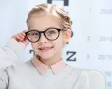 Uśmiechnięta dziewczynka z okularami, u której wykryto bardzo dużą wadę wzroku u dziecka.